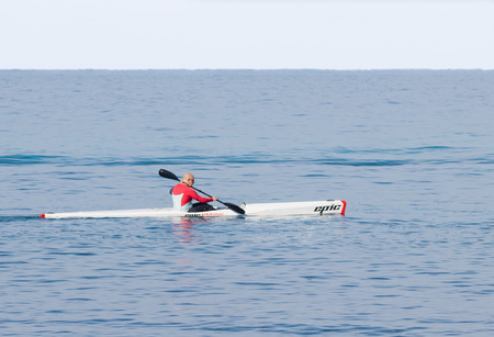 Nahariyya, Israel - February 04, 2017 : Athlete in color tracksuit  training on kayak winter morning on Mediterranean Sea near the coast of Nahariyya, Israelのeditorial素材