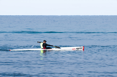 Nahariyya, Israel - February 04, 2017 : Athlete in color tracksuit  training on kayak winter morning on Mediterranean Sea near the coast of Nahariyya, Israelのeditorial素材