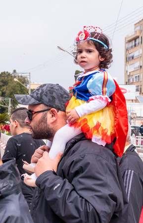 Nahariya, Israel, March 10, 2017: Girl dressed like a princess, sits on her father's shoulders and looks at the traditional annual parade "Adloyada" in Nahariya, Israelのeditorial素材