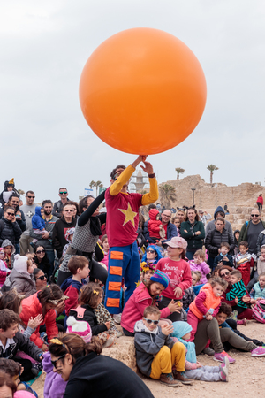 Caesarea, Israel, March 11, 2017 : Participant of the Purim festival dressed in costume of clown shows his art for children in Caesarea, Israelのeditorial素材