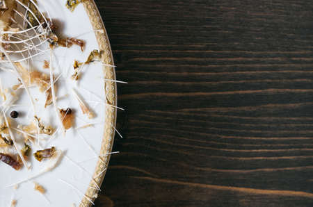 Fish bones on a single white plate. Wooden table background with copy spaceの写真素材