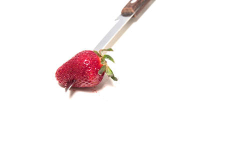 Strawberry is pierced through with a knife blade. A little juice on a white backgroundの写真素材
