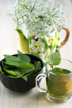 Nettle tea on a wooden table and wild flowersの写真素材