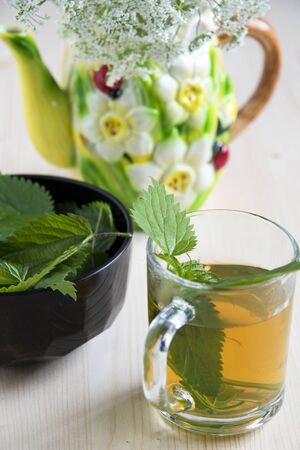 Nettle tea on a wooden table and wild flowers in a ceramic kettleの写真素材