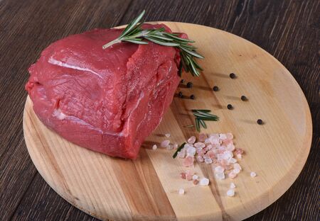 Raw fresh meat with rosemary on a round cutting boardの写真素材