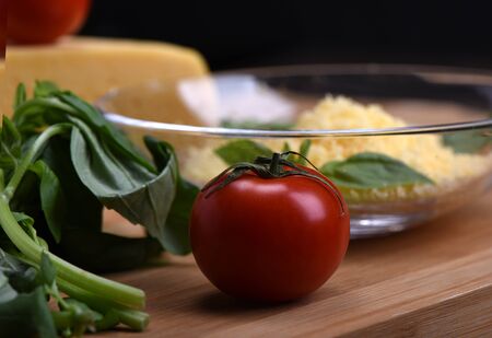 Tomato with basil, cheese in the backgroundon a cutting boardの写真素材