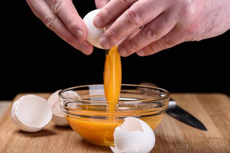 Egg yolk in a bowl eggshells and knife lays next to a bowlの写真素材