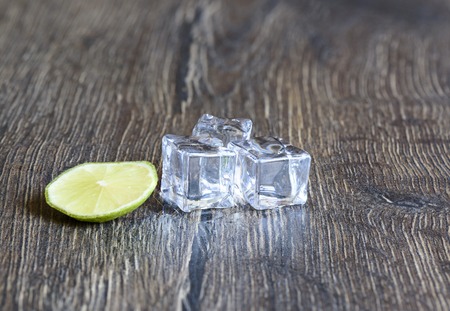 Cubes of ice and lime on a wooden tableの写真素材