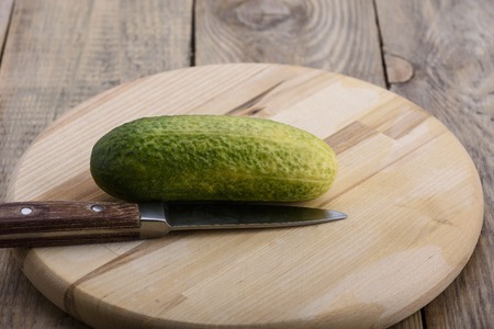 Fresh cucumber and a knife on a cutting boardの写真素材
