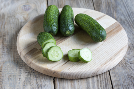 Three whole fresh cucumber and slices of cucumber on a cutting bの写真素材