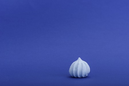 Blue meringue isolated on blue background with space for textの写真素材