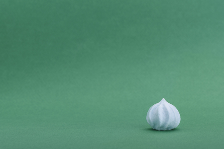Blue meringue isolated on green background with space for your textの写真素材