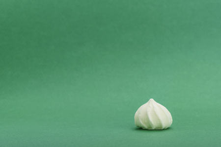 Yellow meringue isolated on green background with space for your textの写真素材