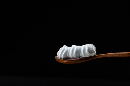 Wooden spoon with three blue meringues isolated on a black background close upの写真素材
