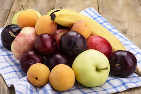 Rustic style. Fruit on a kitchen towel, apples, plums, apricots and bananaの写真素材