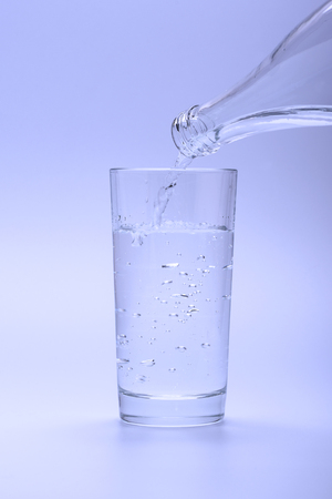 Fresh cold water pouring into a glass from a bottleの写真素材