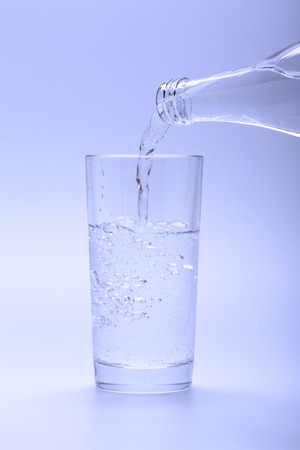 Cold mineral water pouring into a glass from a bottleの写真素材