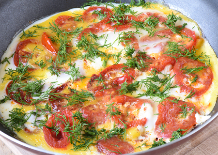 Scrambled eggs with tomatoes and dill in a frying pan close upの写真素材