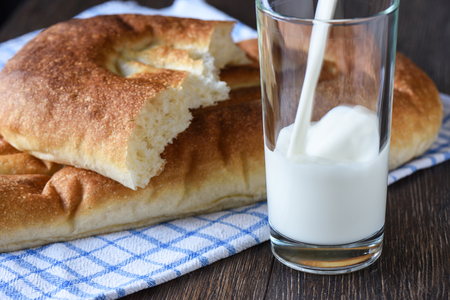 Rustic style. Milk is poured into a glass, bread on a kitchen towel. Close upの写真素材