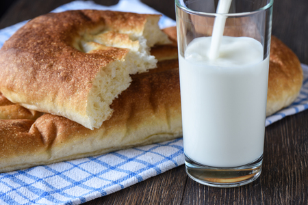 Rustic style. Bread on a kitchen towel, milk is poured into a glassの写真素材