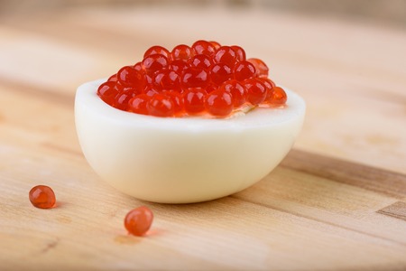 Chicken egg with red caviar close up. Gourmet food, appetizer. Close-up salmon caviar.