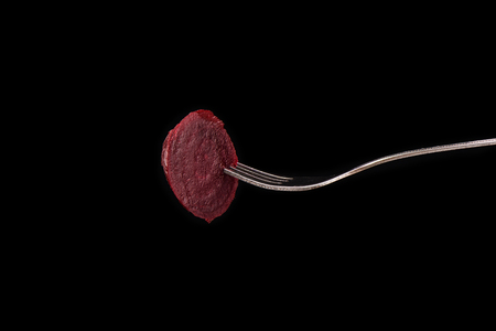 Slice of boiled beets on a fork isolated on a black backgroundの写真素材