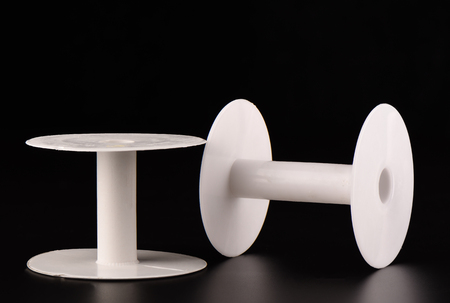 Two plastic empty spools of lace on a black backgroundの写真素材