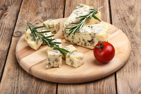 Blue mold cheese, rosemary and fresh tomato on a rustic wooden tableの写真素材