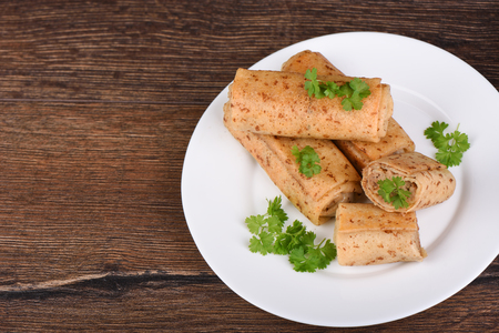 Pancake rolls with meat filling, served with fresh parsley. Traditional russian food on wooden...