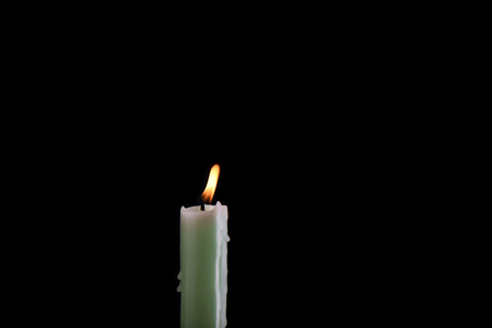 Burning pale green candle isolated on a black background. Copy spaceの写真素材