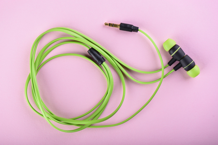 Green headphones or earphones isolated on a pink backgroundの写真素材