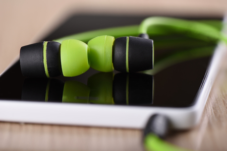 Smartphone and green earphones on the tableの写真素材