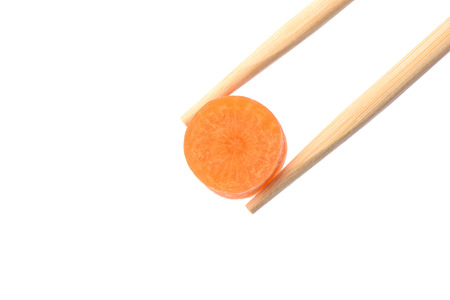 Chopsticks with a circle of ripe carrots isolated on white background. Copy spaceの写真素材
