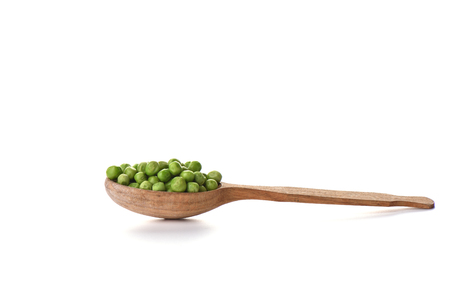 Green peas on a wooden spoon isolated on white background. Border design. Copy spaceの写真素材