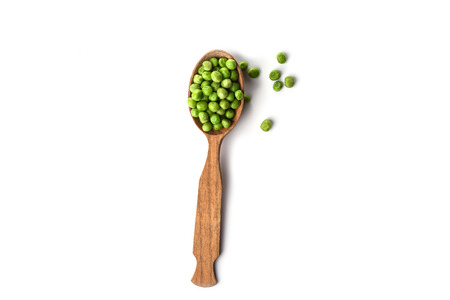 Green peas in wooden spoon isolated on white background. Several peas on a white background. Copy spaceの写真素材