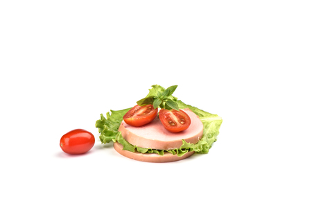 Two pieces of boiled sausage with sliced tomatoes and a leaf of lettuce on a white background. Traditional Russian sausage. Copy spaceの写真素材