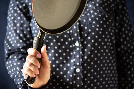 Pan in the hands of the girl. A girl with a pink manicure holding a frying pan. Close up