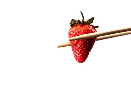Chopsticks with ripe strawberry over white background. Copy spaceの写真素材