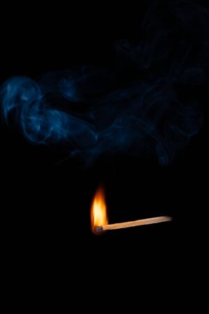 Lighting matches at the moment when it explodes. Burning wooden match with blue smoke over black...