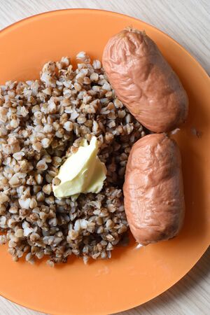 The traditional dish of Russian cuisine. Boiled sausages with buckwheat garnish with butter. Rustic style.の写真素材