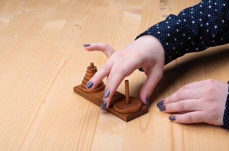 Girl plays puzzle tower of hanoi. Dark manicure. Puzzle concept.