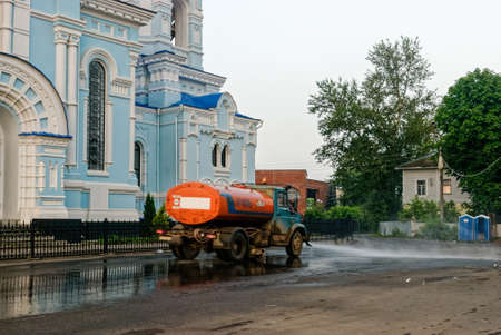 Kaluga Region, the city of Maloyaroslavets, Russia June 25, 2013: Street sprinkler in the early morning on the city street. Washes dirt off the road.のeditorial素材