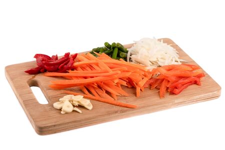 Sliced onions, garlic, carrots, sweet peppers on a cutting board. Sliced vegetables on a cutting board over a white background. Copy space.の写真素材