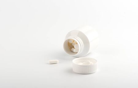 White pills and plastic bottle on a white background. Health concept. Copy space.