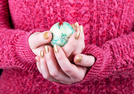 Girl with a golden manicure holds Chinese baoling health balls in her fingers. Girl in a red knitted...
