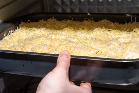Soft focus setting the lasagna mold into the oven. Making lasagna at home.