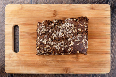 A whole loaf of rustic rye bread with sunflower seeds. Bread on a cutting board. Top view. Close up.