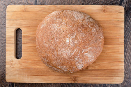 A whole loaf of wheat rye bread on a cutting board. Top view. Close up.