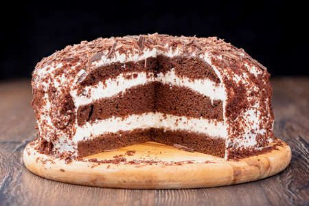 Cut of puff chocolate cream cake sprinkled with chocolate chips. Homemade cake.