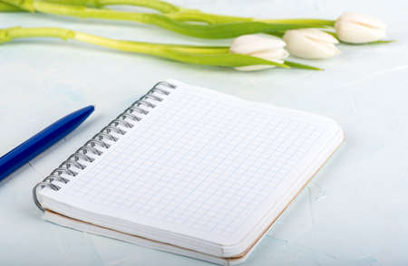 Soft focus notepad with checkered sheets and blurred tulips in the background.の写真素材